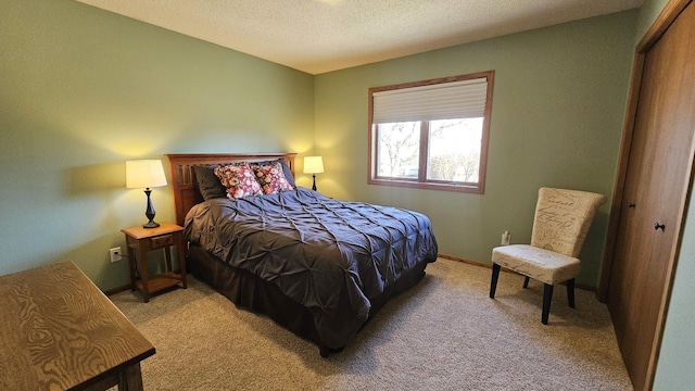 bedroom with a closet, baseboards, light colored carpet, and a textured ceiling