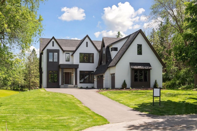 view of front of home featuring a front lawn, a garage, driveway, and a shingled roof