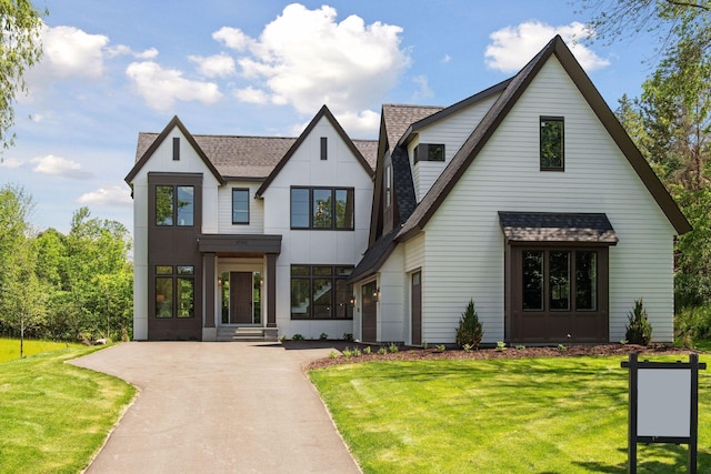 view of front of property featuring aphalt driveway, a shingled roof, and a front yard