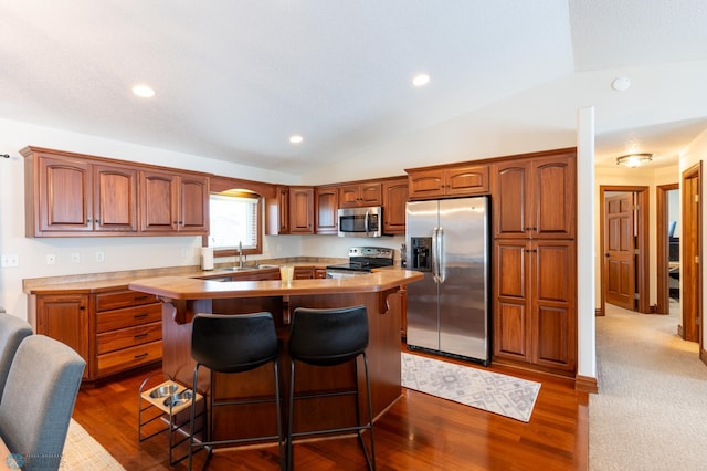 kitchen with appliances with stainless steel finishes, light countertops, and lofted ceiling