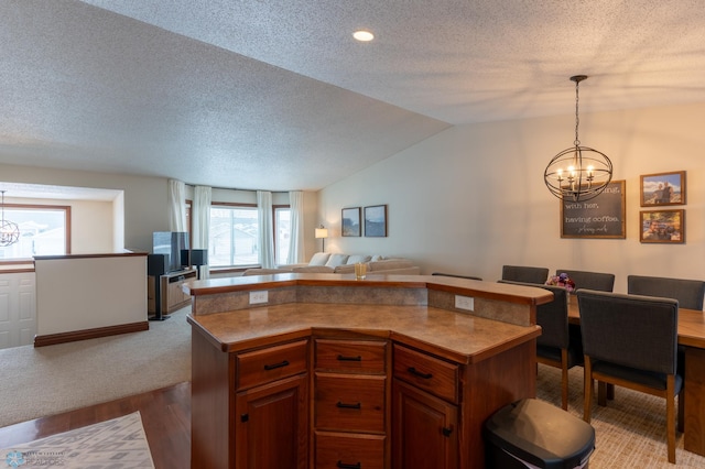 kitchen featuring open floor plan, a center island, an inviting chandelier, vaulted ceiling, and hanging light fixtures