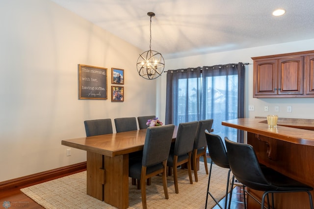 dining area with an inviting chandelier, baseboards, light wood-type flooring, and a textured ceiling