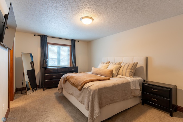 bedroom featuring light colored carpet, baseboards, and a textured ceiling