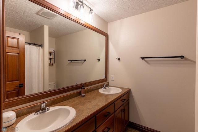 full bath with a sink, visible vents, toilet, and a textured ceiling