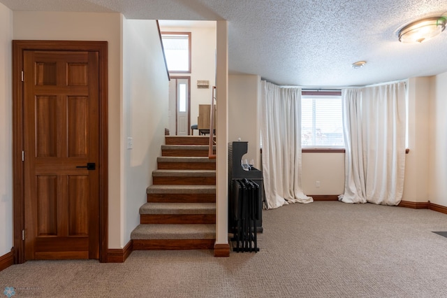 staircase featuring baseboards, carpet floors, and a textured ceiling