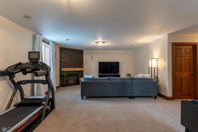 living room with baseboards, light carpet, a textured ceiling, and a glass covered fireplace