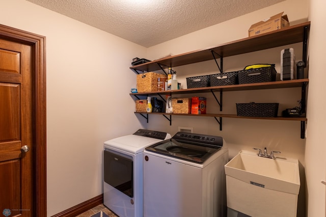 laundry room featuring baseboards, laundry area, a sink, a textured ceiling, and washer and clothes dryer