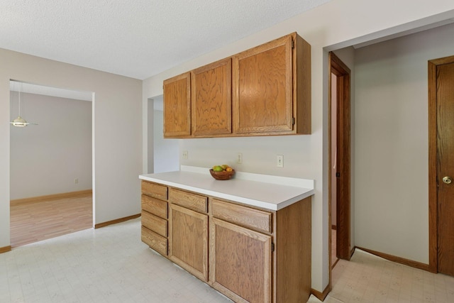 18884 Pennington Ave, Eden Prairie, MN 55346 - kitchen featuring light flooring, light countertops, brown cabinetry, and a textured ceiling