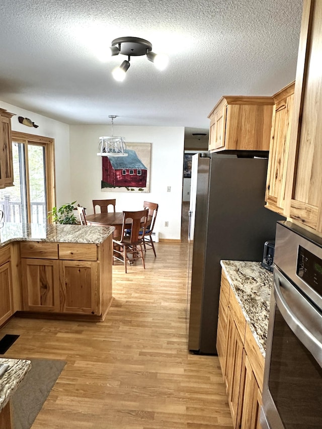 1421 Riverside Dr NW, Baudette, MN 56623 - kitchen featuring stainless steel appliances, light wood-style flooring, a peninsula, a textured ceiling, and a chandelier