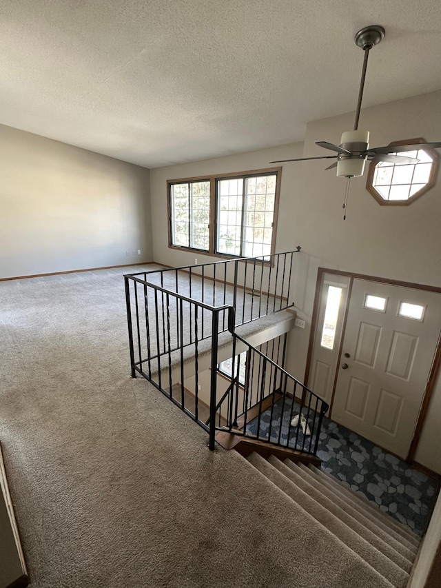 carpeted entrance foyer with baseboards, a textured ceiling, and a ceiling fan