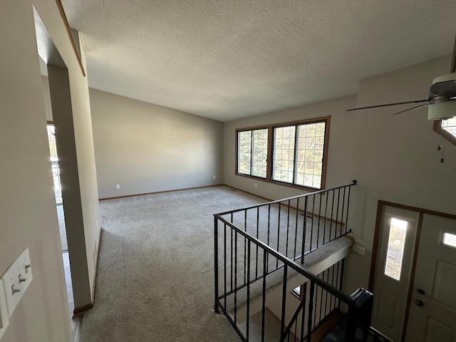 interior space featuring baseboards, carpet floors, a textured ceiling, and a ceiling fan