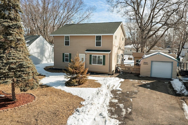 view of front of house with aphalt driveway, a detached garage, and an outbuilding