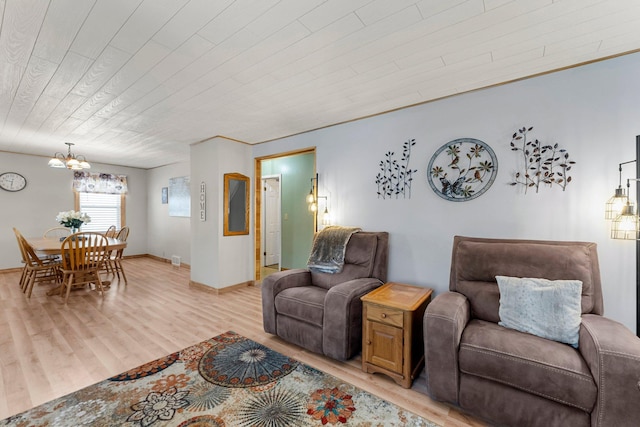 living room with light wood finished floors, a chandelier, wooden ceiling, and baseboards