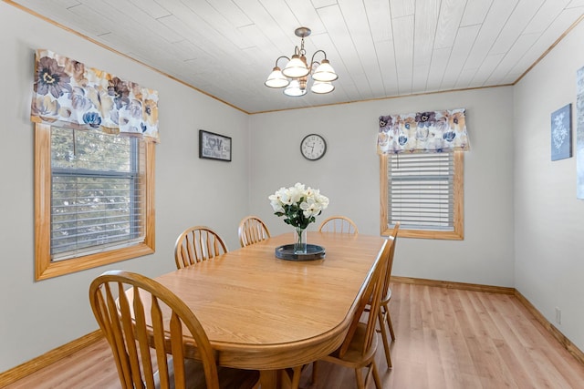 dining room featuring light wood finished floors, a notable chandelier, baseboards, and ornamental molding