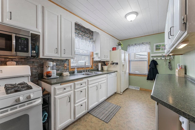 kitchen with visible vents, a sink, dark countertops, white cabinetry, and white appliances