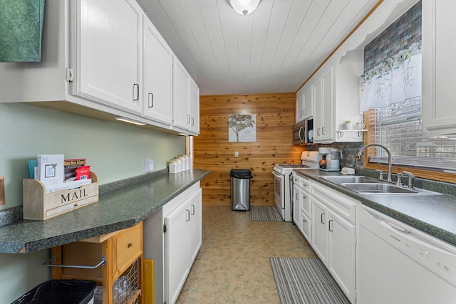 kitchen with white appliances, wooden walls, white cabinets, and a sink