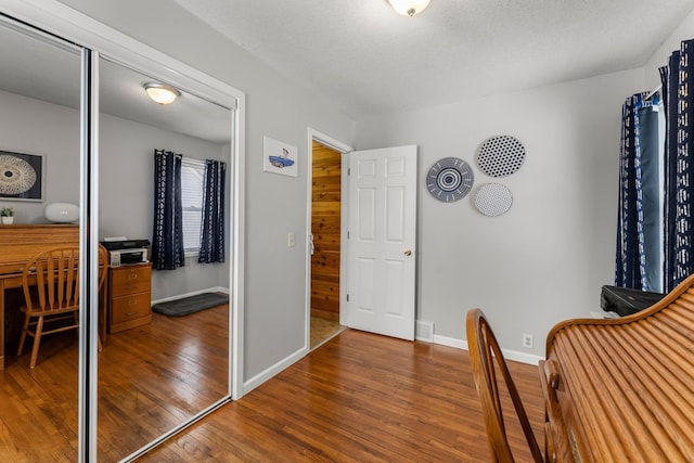 interior space featuring a textured ceiling, baseboards, and wood-type flooring