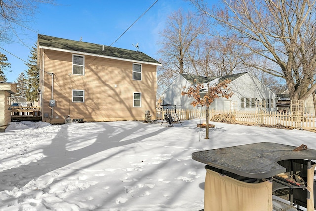 snow covered back of property with fence