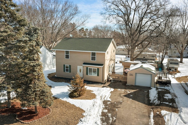 view of front of house featuring an outbuilding, fence, driveway, a shingled roof, and a detached garage