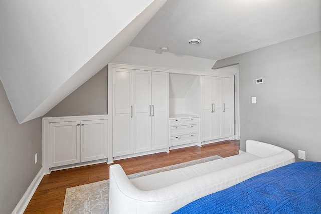 bedroom featuring lofted ceiling, baseboards, and dark wood-style flooring