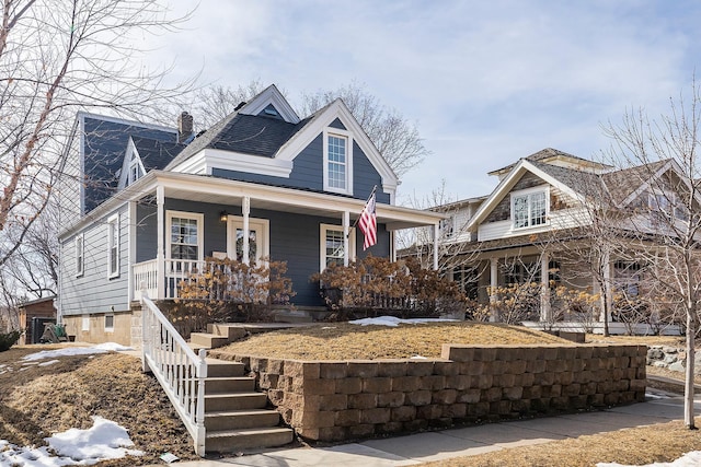 view of front of house with a porch, a chimney, and stairs