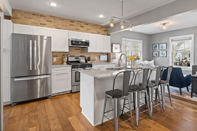 kitchen with a sink, light wood-type flooring, appliances with stainless steel finishes, and white cabinets