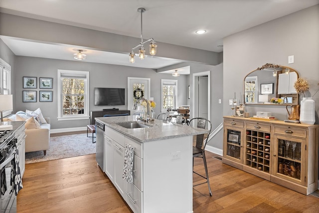 kitchen featuring light wood finished floors, open floor plan, a breakfast bar area, and a sink