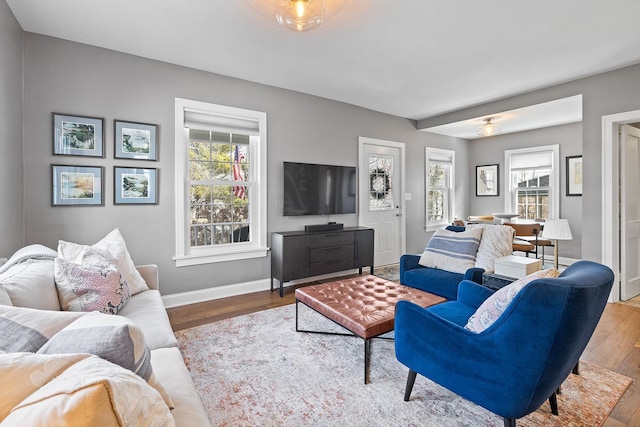 living area featuring a healthy amount of sunlight, baseboards, and wood finished floors