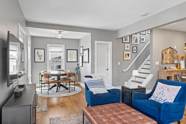 living room featuring a wealth of natural light, light wood-style flooring, stairs, and baseboards