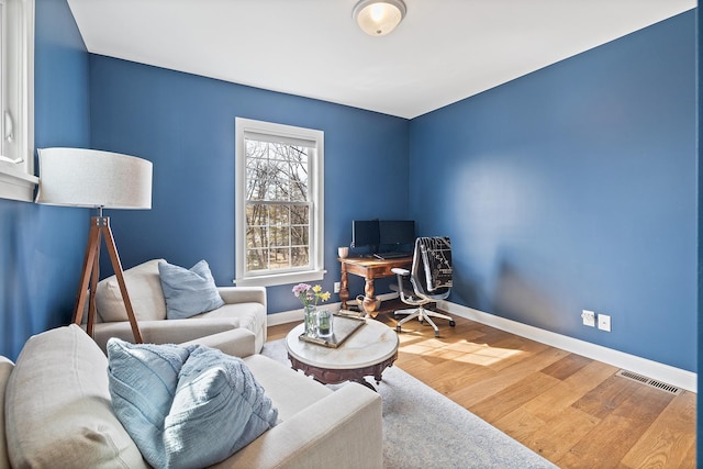 living area featuring visible vents, wood finished floors, and baseboards