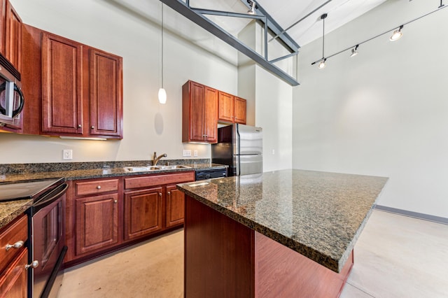 kitchen featuring pendant lighting, track lighting, a sink, appliances with stainless steel finishes, and a towering ceiling