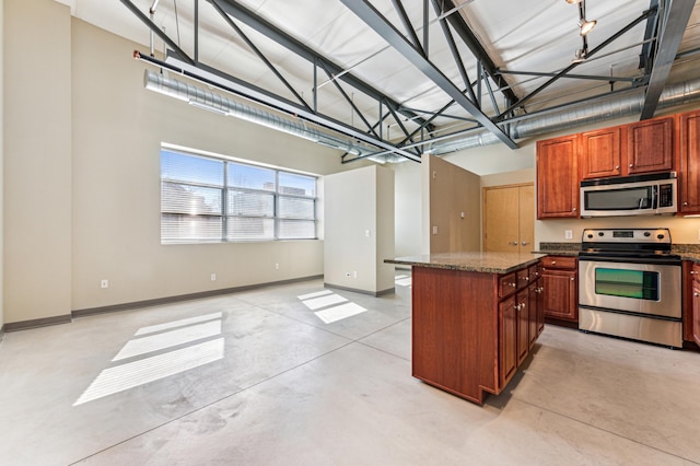 kitchen with concrete floors, baseboards, appliances with stainless steel finishes, and a center island