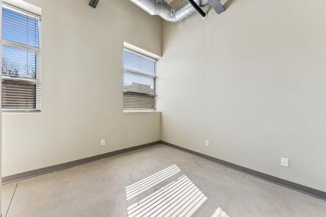 spare room with a healthy amount of sunlight, concrete flooring, and baseboards