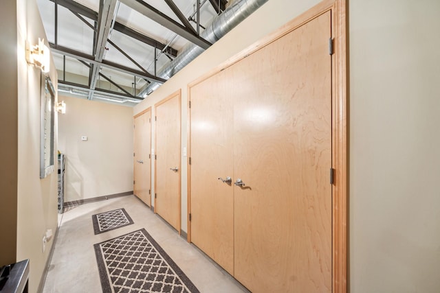 hallway with baseboards and concrete flooring