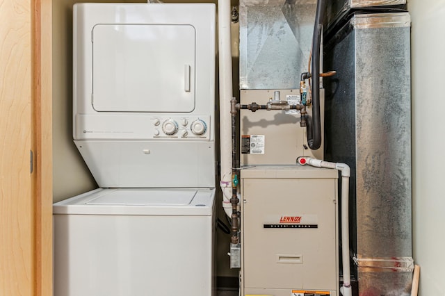 laundry room featuring heating unit, stacked washer and dryer, and laundry area