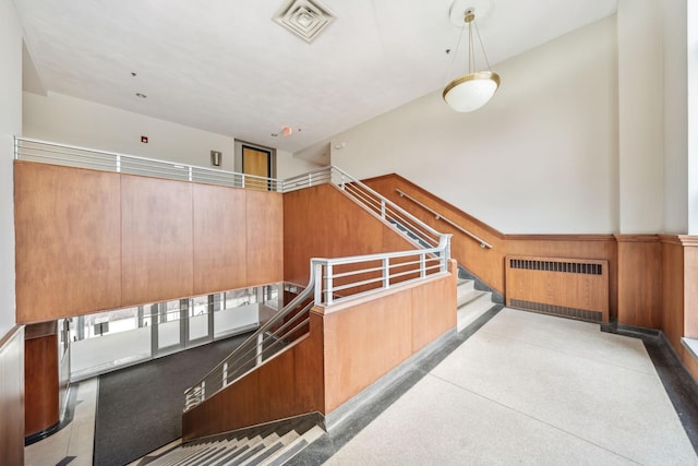 interior space featuring visible vents, wood walls, radiator heating unit, wainscoting, and speckled floor