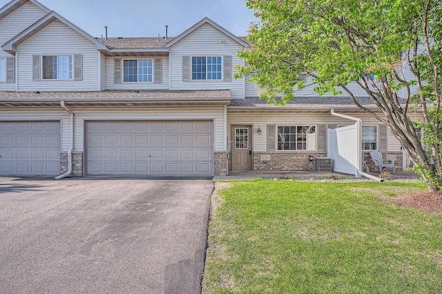 16786 Embers Ave, Lakeville, MN 55024 - view of property featuring a front yard, asphalt driveway, an attached garage, central AC, and brick siding
