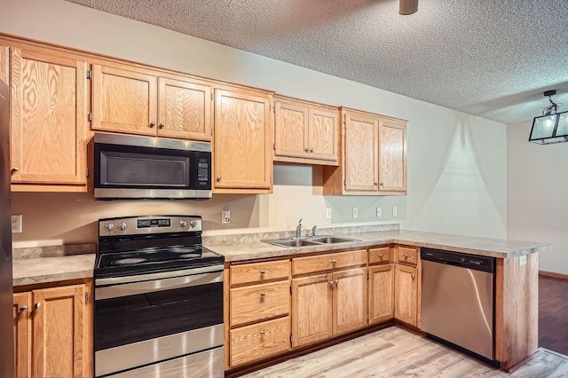 16786 Embers Ave, Lakeville, MN 55024 - kitchen featuring appliances with stainless steel finishes, a sink, a textured ceiling, light countertops, and light wood-style floors