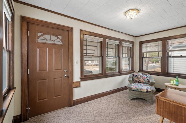 foyer entrance with carpet flooring, baseboards, and ornamental molding