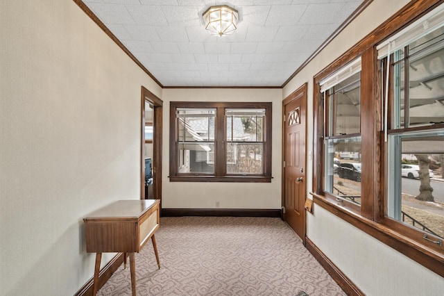 hallway featuring baseboards, carpet floors, and crown molding