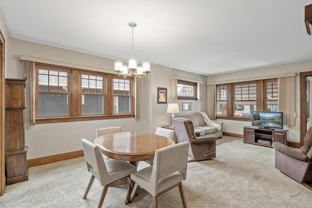 dining space featuring light carpet, a notable chandelier, and baseboards