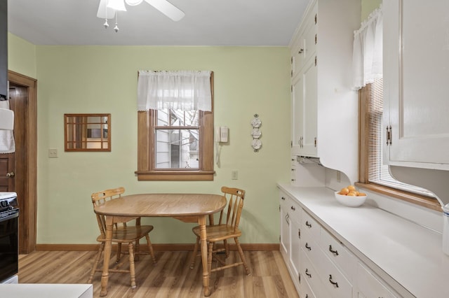 dining space with baseboards, light wood-style floors, and ceiling fan