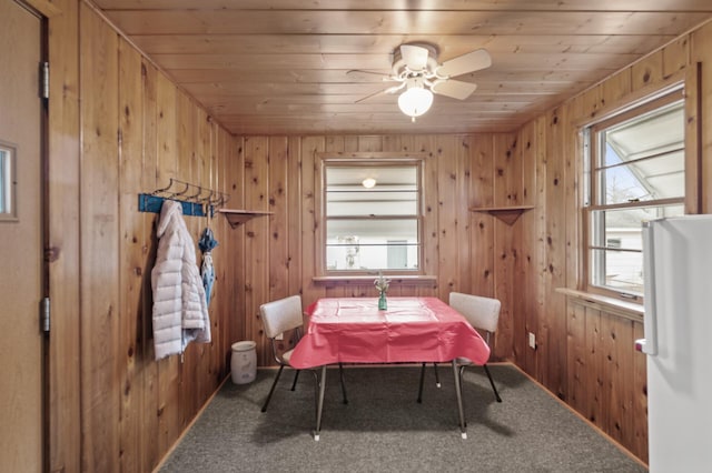 carpeted dining space with plenty of natural light, wooden ceiling, and wood walls