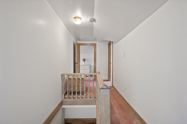 hallway featuring carpet and baseboards