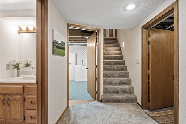 stairs featuring baseboards, carpet, and a textured ceiling