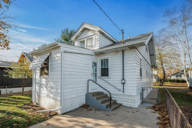 rear view of property featuring entry steps, a gate, and fence