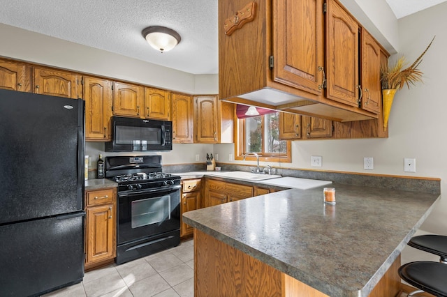 28510 142nd St NW, Zimmerman, MN 55398 - kitchen featuring black appliances, a sink, a peninsula, brown cabinetry, and light tile patterned floors