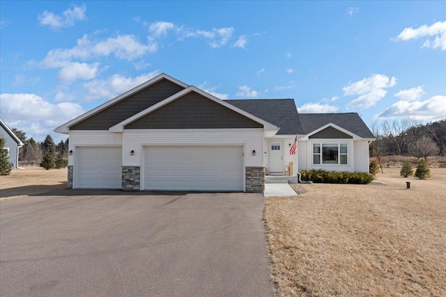 view of front of house with aphalt driveway, stone siding, a front lawn, and an attached garage