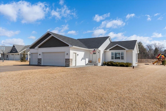 single story home with a garage, driveway, a front lawn, and stone siding