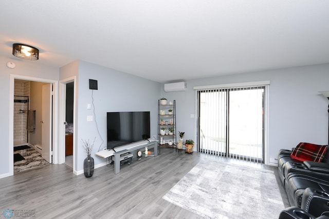 living room featuring light wood-style flooring, a wall mounted AC, and baseboards